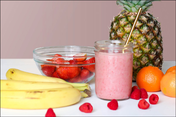 Fruit smoothie ingredients, such as a pineapple, strawberries, bananas, raspberries, and tangerines