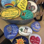A bucket of painted rocks with encouraging messages like "You matter" and "Hang on. Tomorrow is a new day." and "Never give up. This too shall pass."