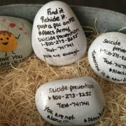The backside of painted rocks which feature the Suicide Prevention Hotline phone number, 1-800-273-8255, or text 741741
