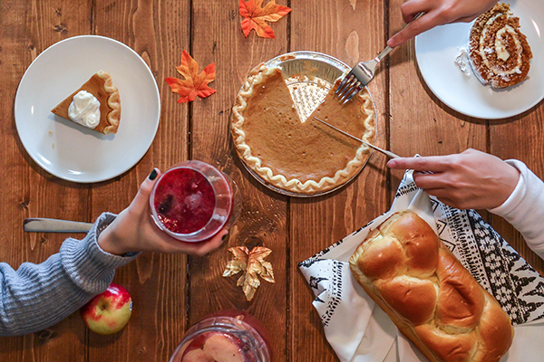 Friends enjoying pumpkin pie, challah bread, and holiday treats around a table