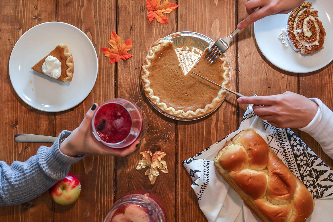 Friends enjoying pumpkin pie, challah bread, and holiday treats around a table