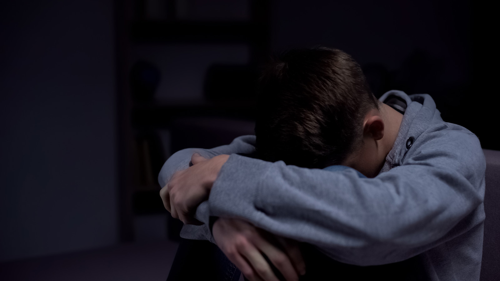 A boy with his head down on his knees looking troubled