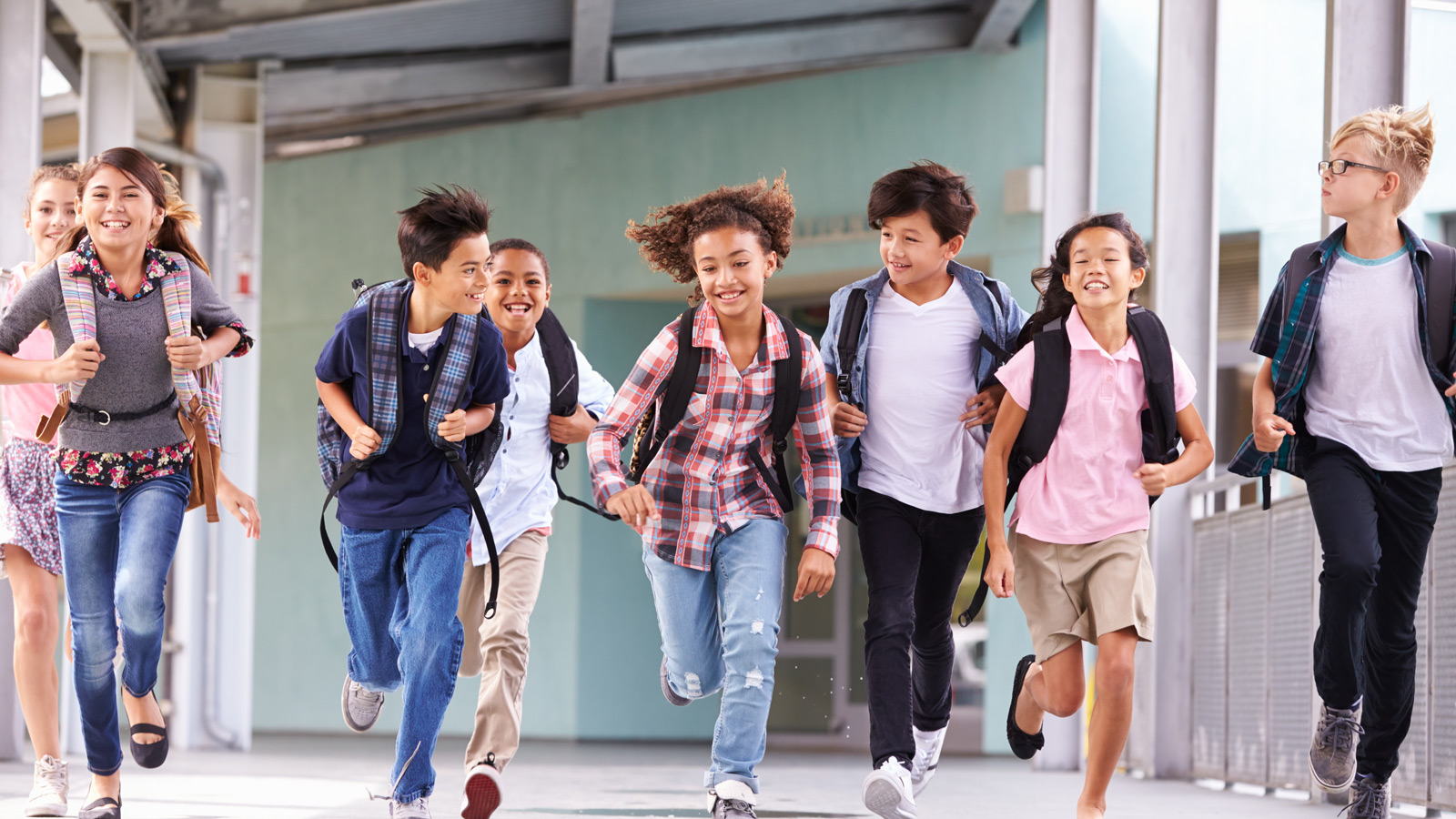 A group of middle school students running down the hallway full of joy
