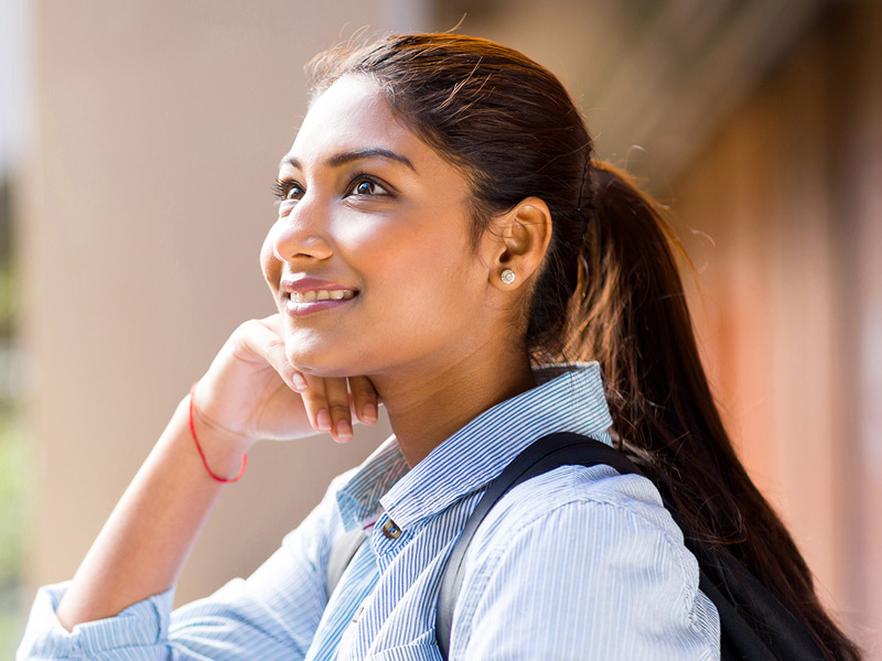A female student smiling and looking upward with a hopeful expression