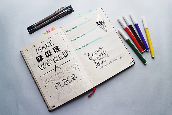 A journal decorated with attractive doodles and the phrase "Make the world a pretty place"