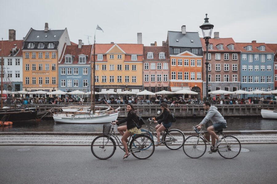 People riding bikes along a colorful harbor in Denmark