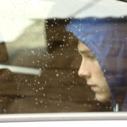 Teenage boy who seems anxious looking out the window on a rainy day