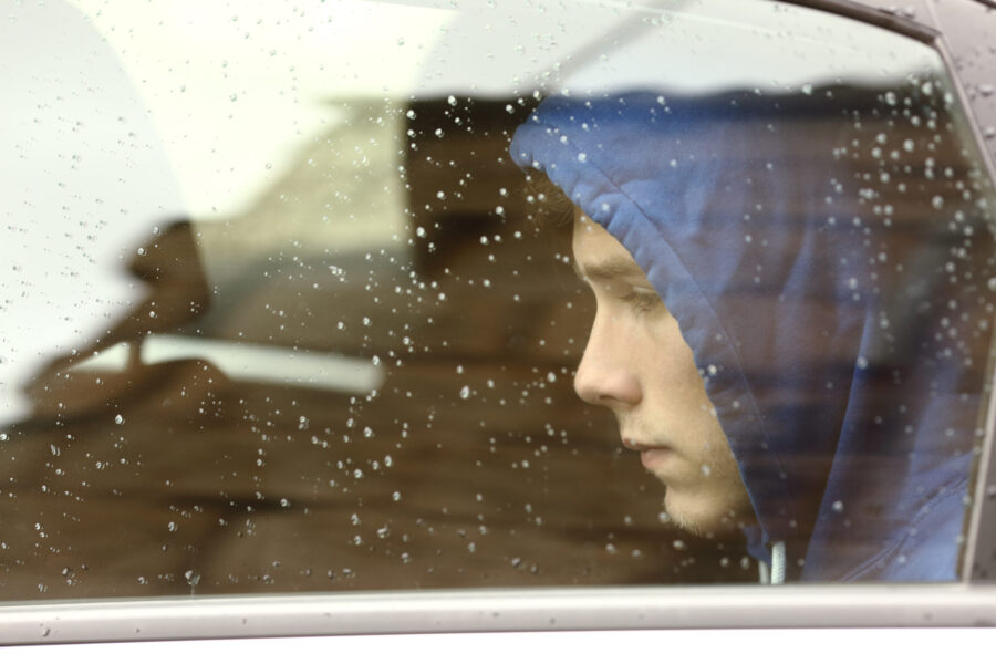 Teenage boy who seems anxious looking out the window on a rainy day